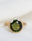 Ring with a green gemstone and gold band on a white background