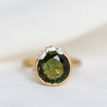 Ring with a green gemstone and gold band on a white background