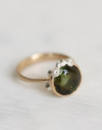 Gold ring with a green gemstone on a light gray background