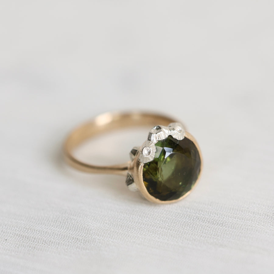 Gold ring with a green gemstone on a light gray background