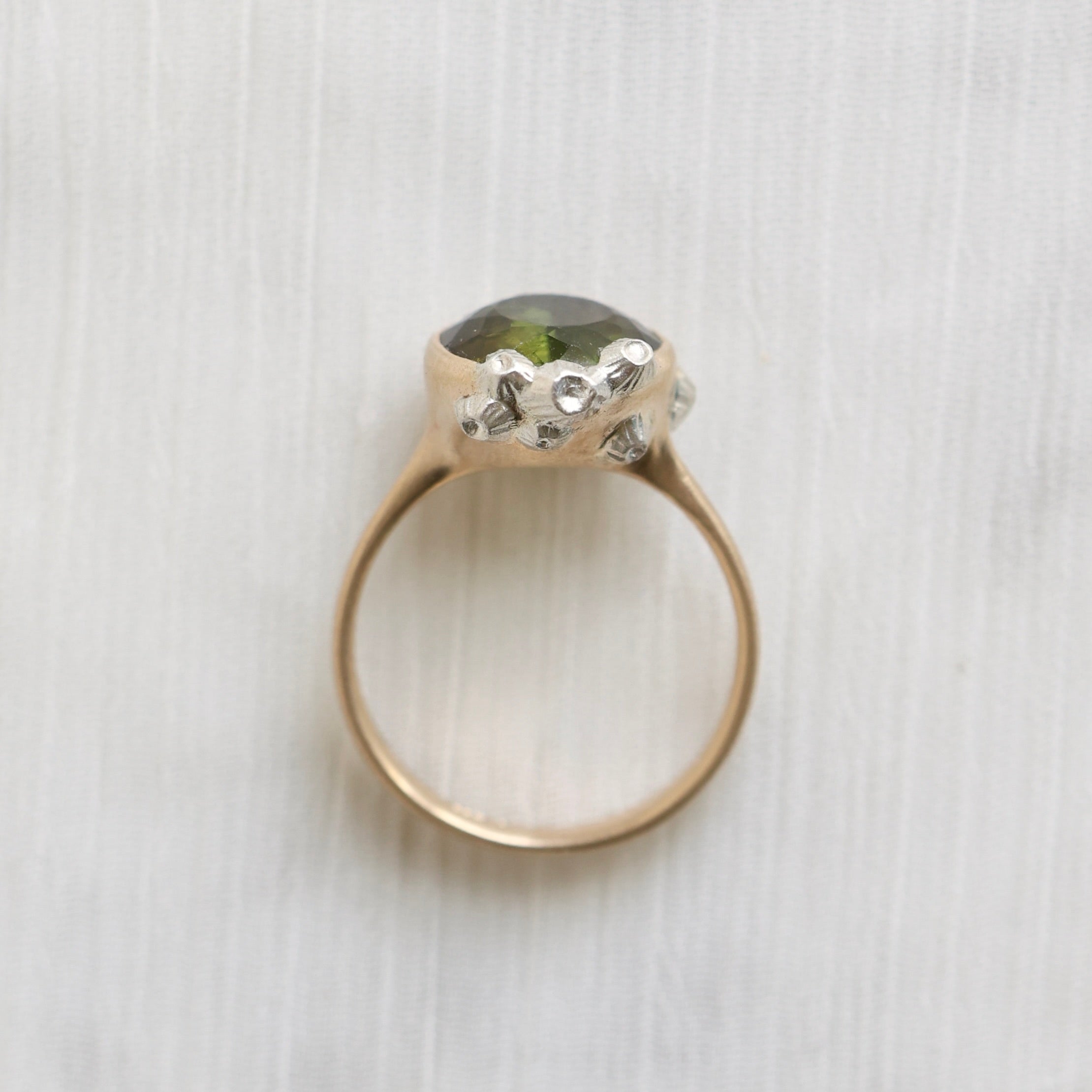 Gold ring with a green gemstone on a white textured background
