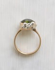 Gold ring with a green gemstone on a white textured background