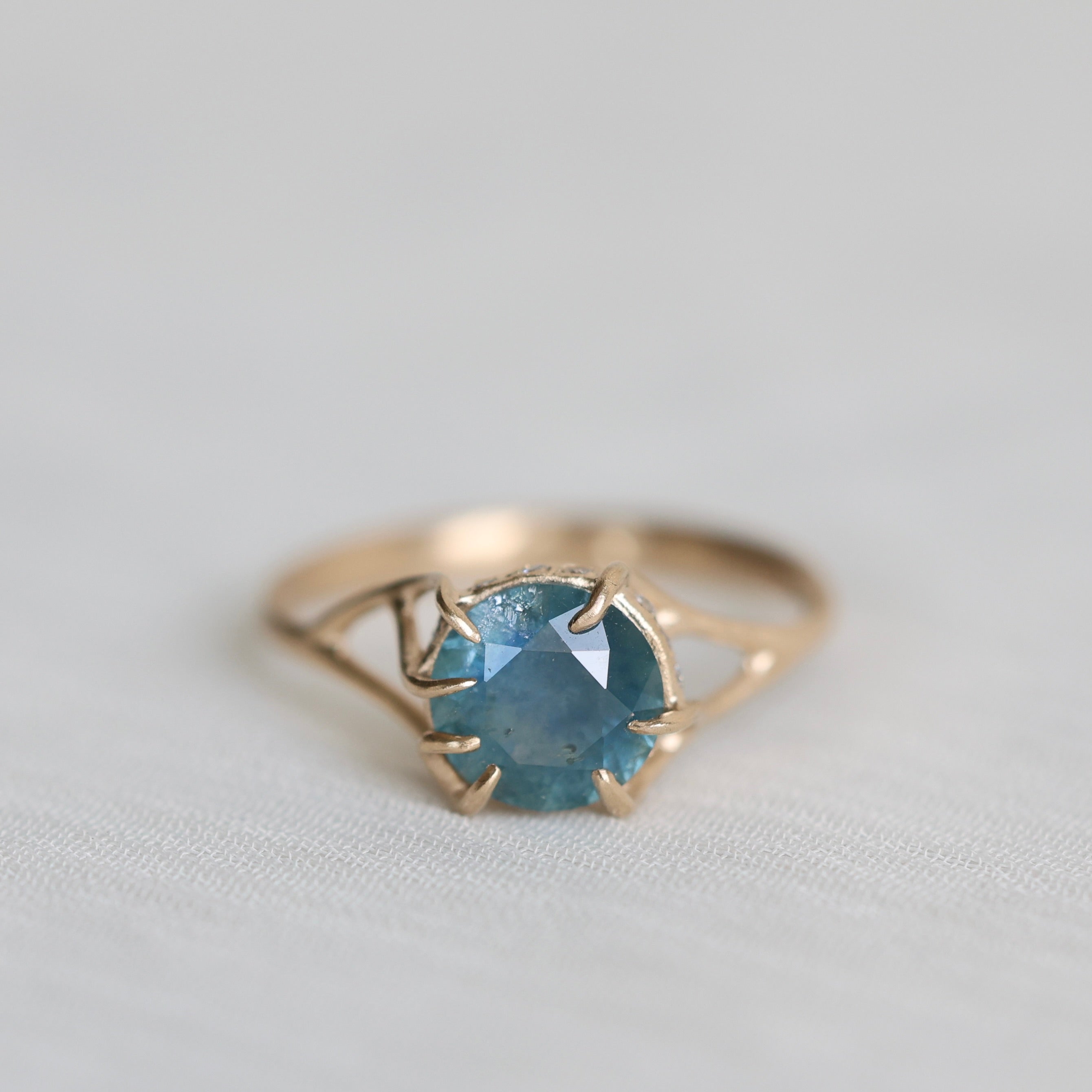 Gold ring with a blue gemstone on a light gray background