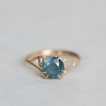 Gold ring with a blue gemstone on a light gray background