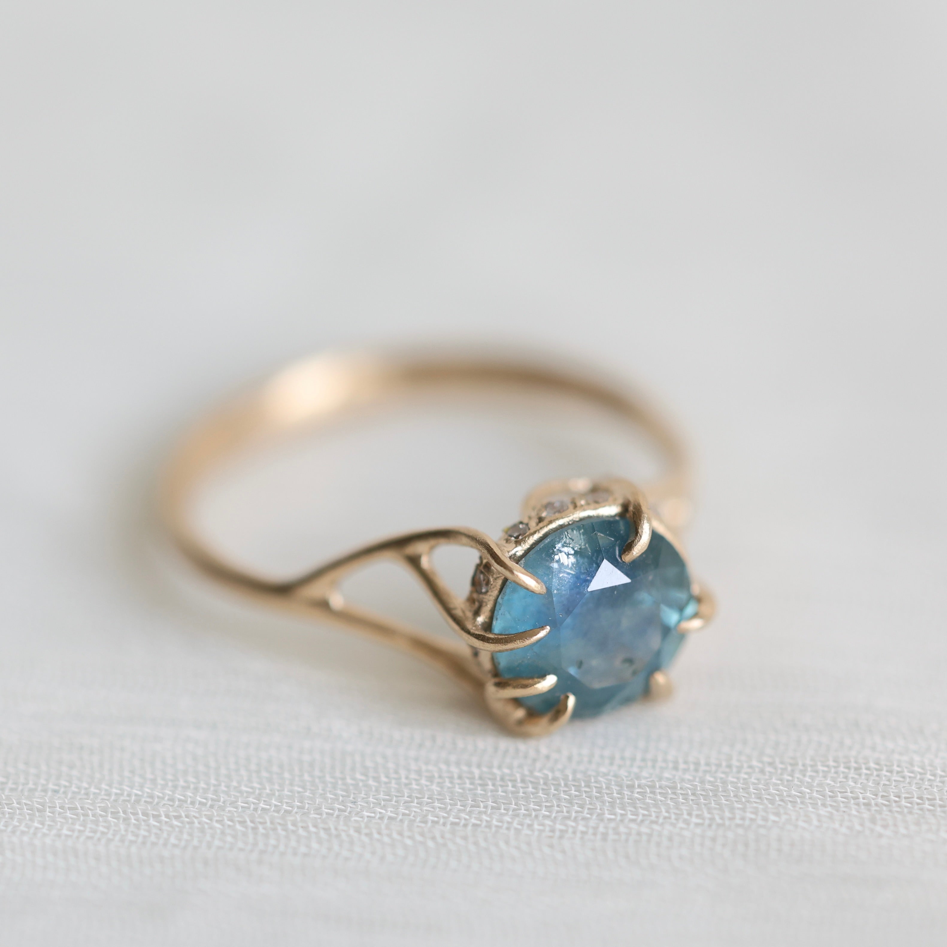 Gold ring with a blue gemstone on a light fabric background