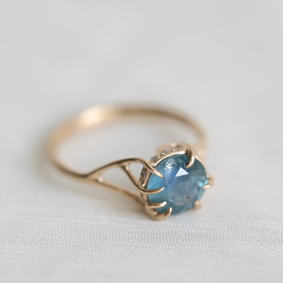 Gold ring with a blue gemstone on a light fabric background