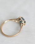 Gold ring with blue gemstone and diamonds on a light fabric background
