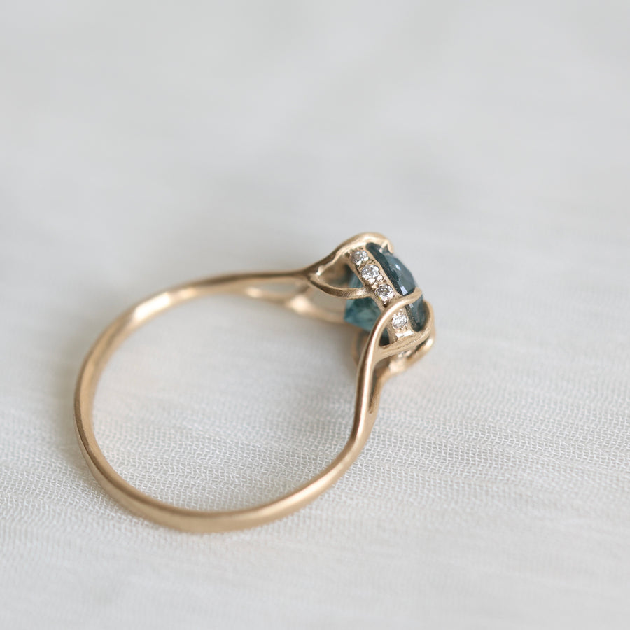 Gold ring with blue gemstone and diamonds on a light fabric background