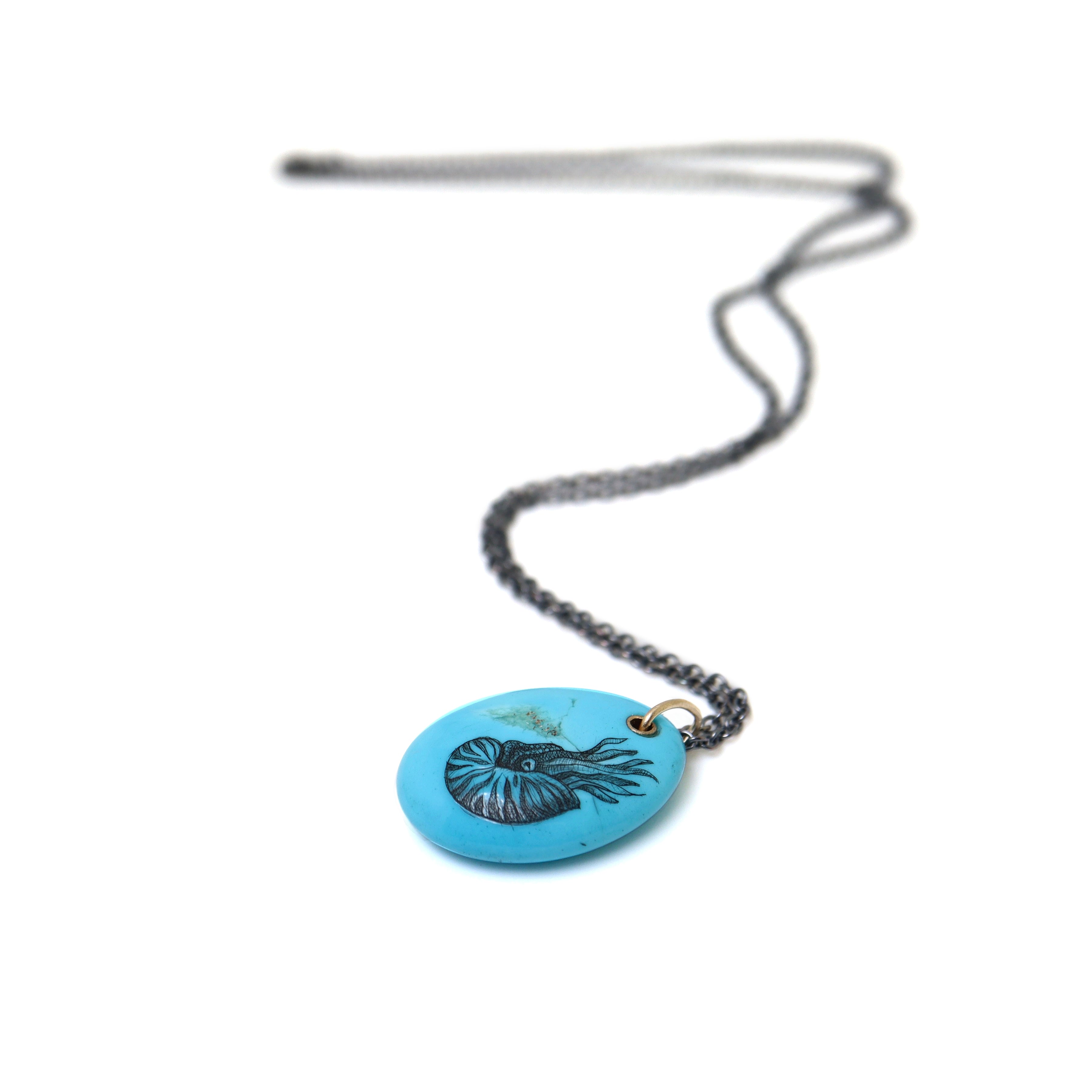 kingman turquoise pendant with inked illustration of a nautilus on oxidized silver chain with gold details