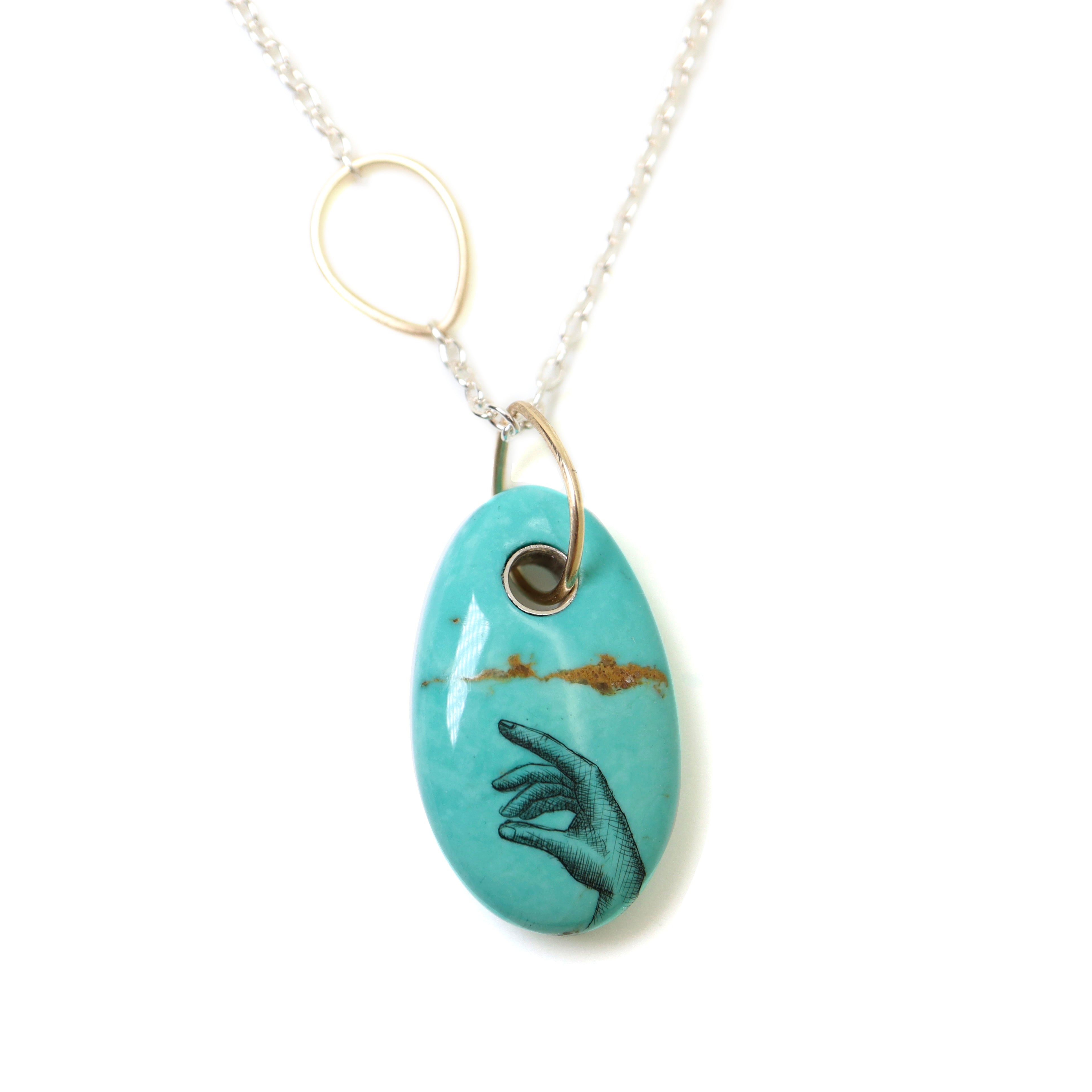 kingman turquoise bead with hand scrimshaw in ink. Pendant necklace with bright silver chain with gold egg link.
