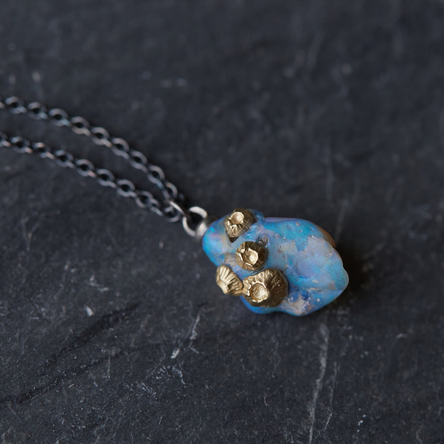 detail view of raw fossilized wood opal necklace with nautical gold barnacles and black silver chain