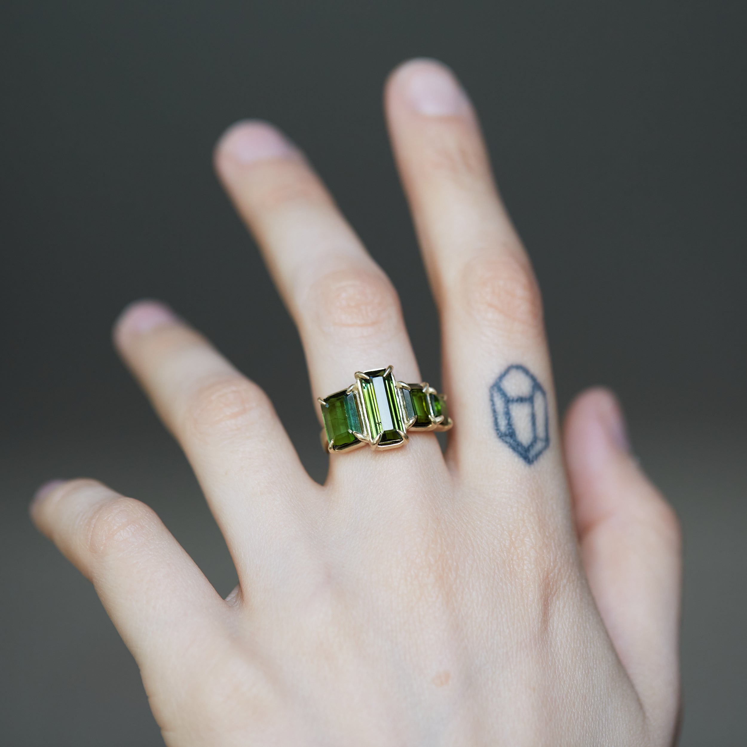 four stone green tourmaline and gold ring on person