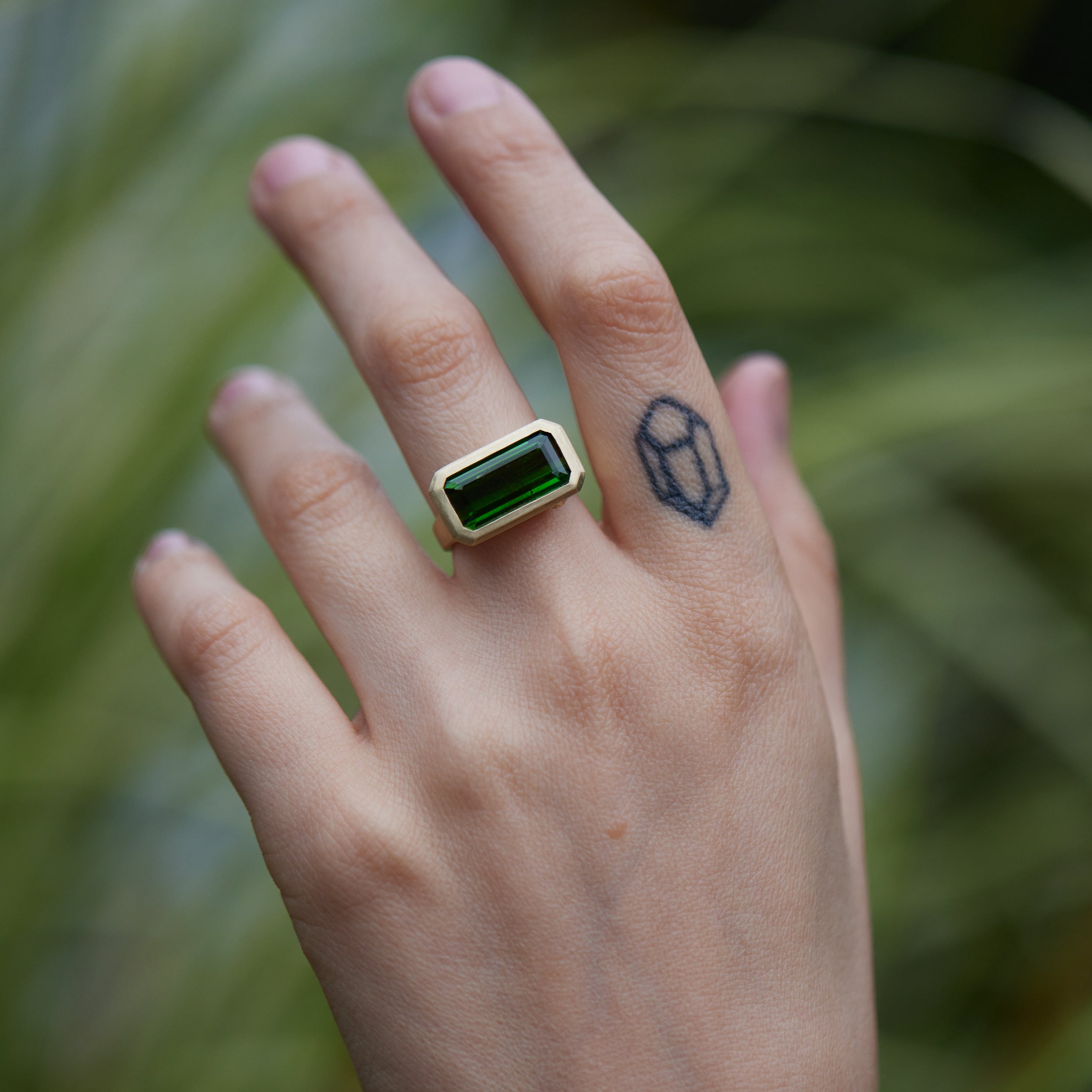 green tourmaline rectangle cut stone ring set in gold with barnacles- on person