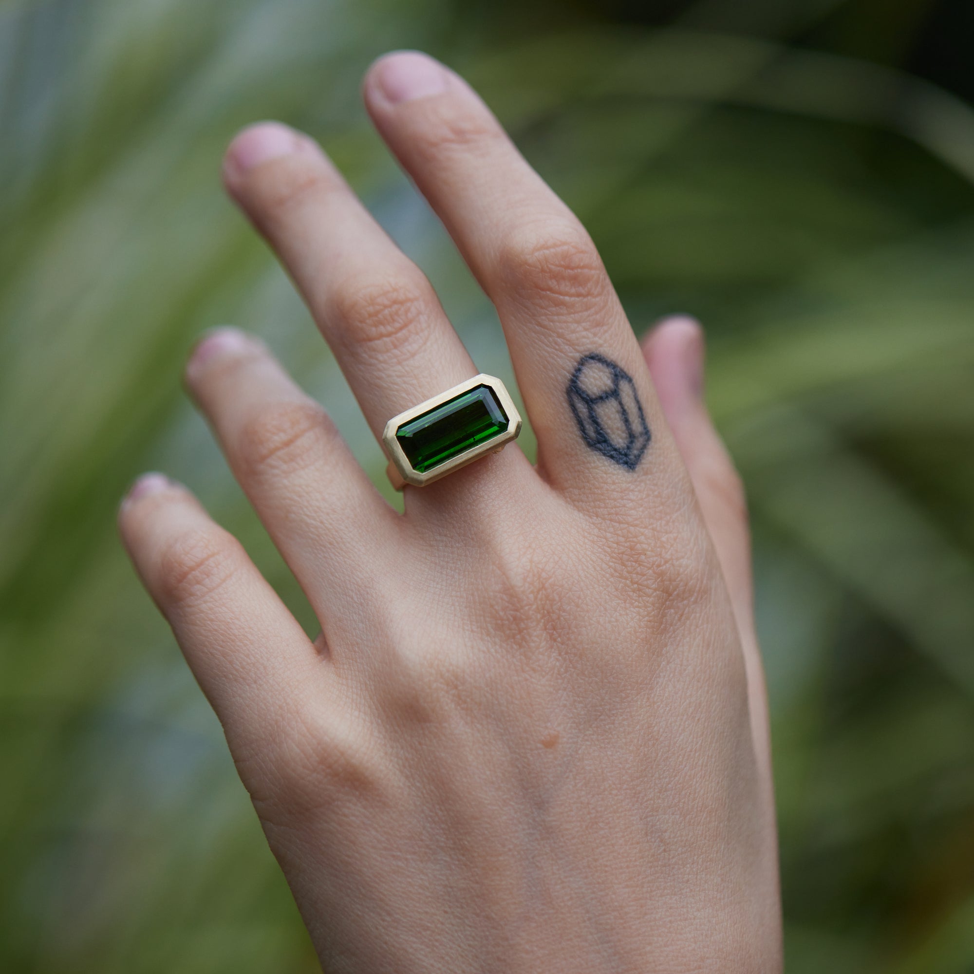 green tourmaline rectangle cut stone ring set in gold with barnacles- on person
