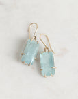 Bright blue stones suspended from gold ear wires
