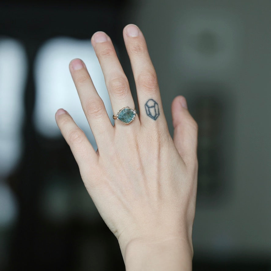 Large aquamarine ring with barnacles on hand with tattoo
