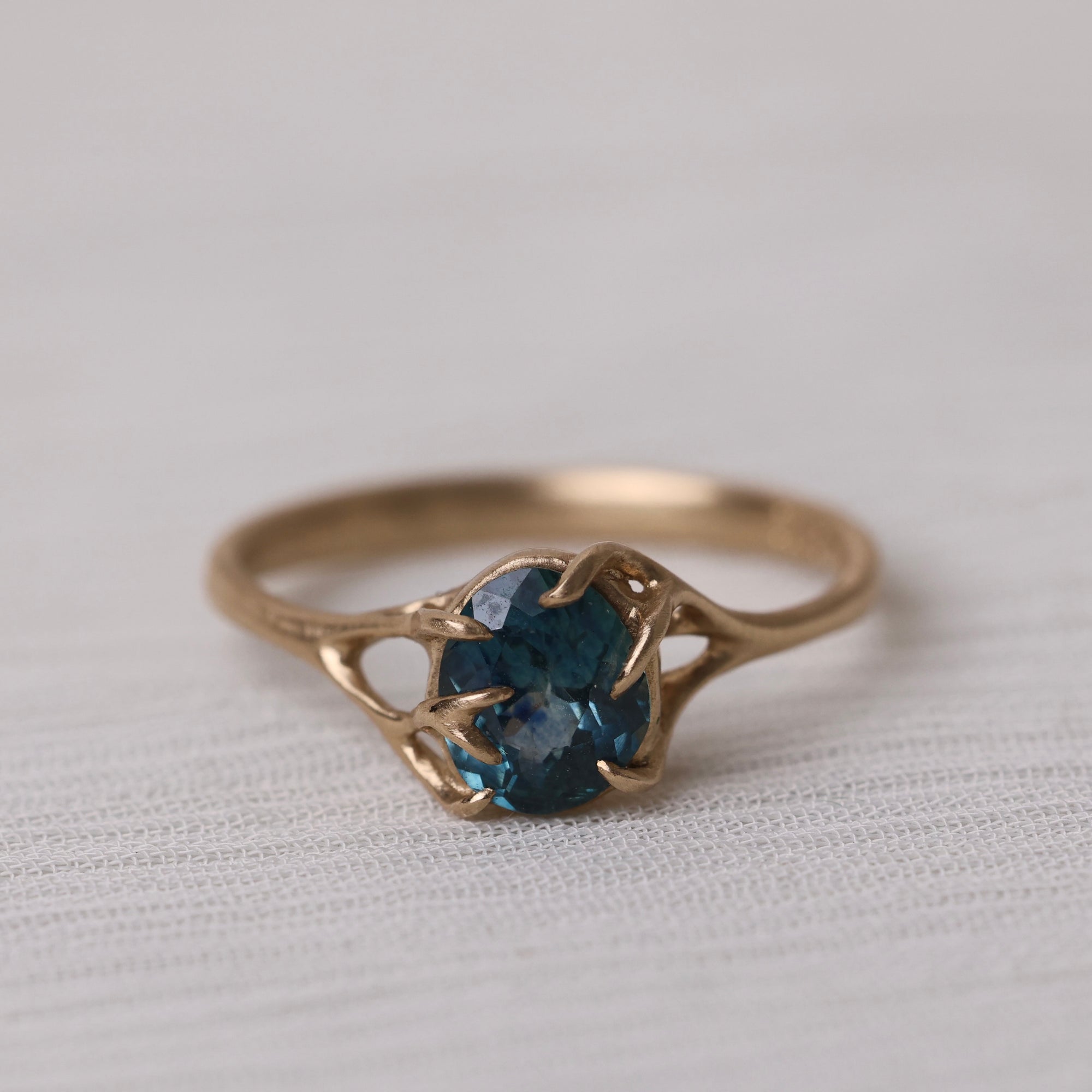 Gold ring with a blue gemstone on a light fabric background