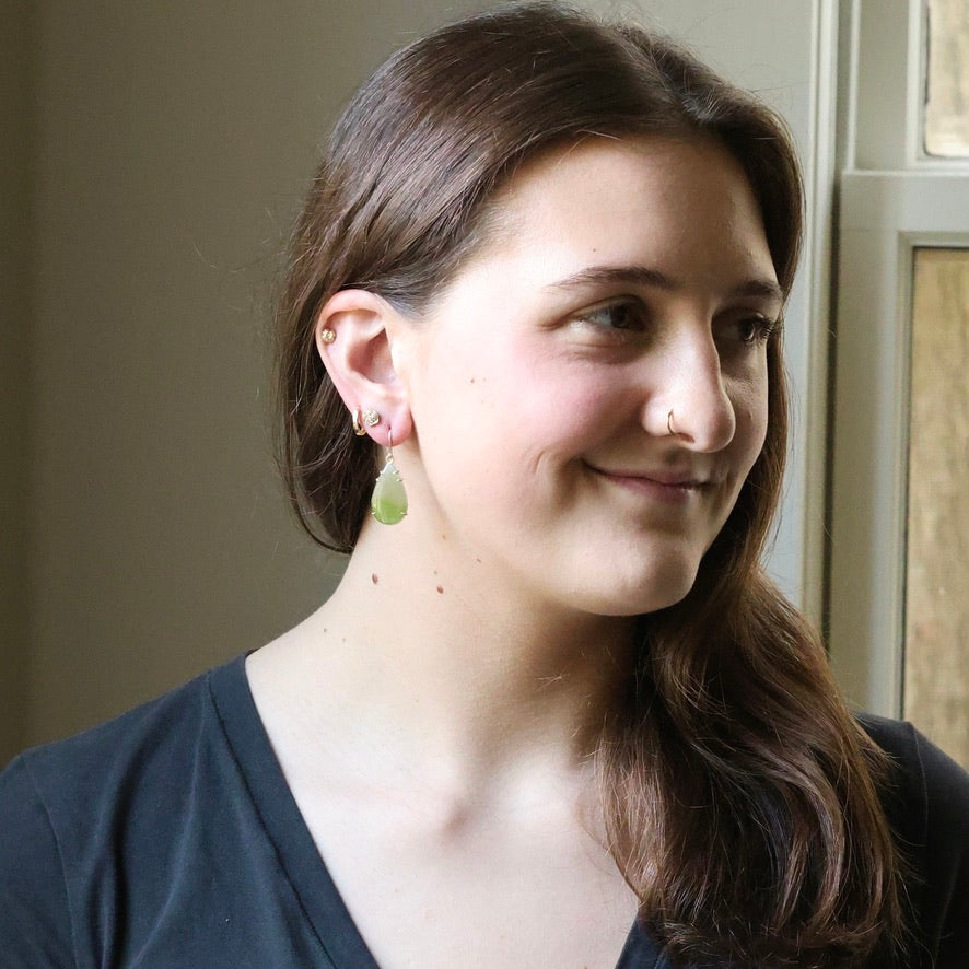 Woman with a nose ring and earrings smiling indoors