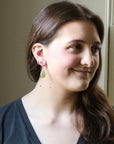 Woman with a nose ring and earrings smiling indoors