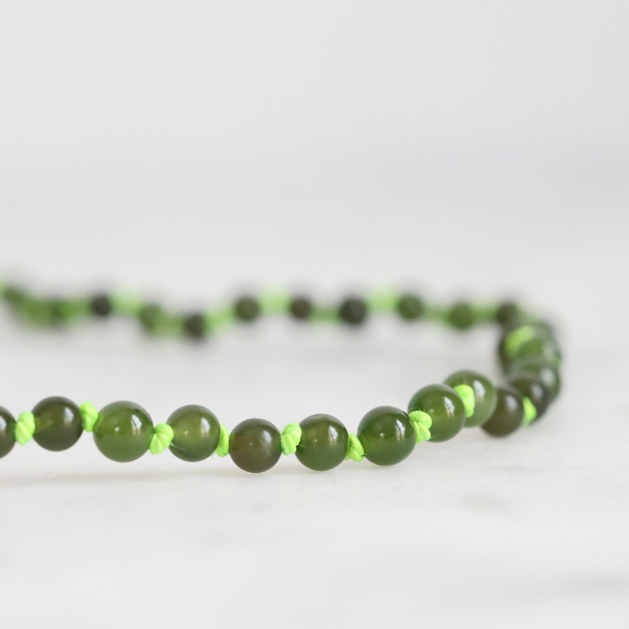 Green beaded necklace on a white background