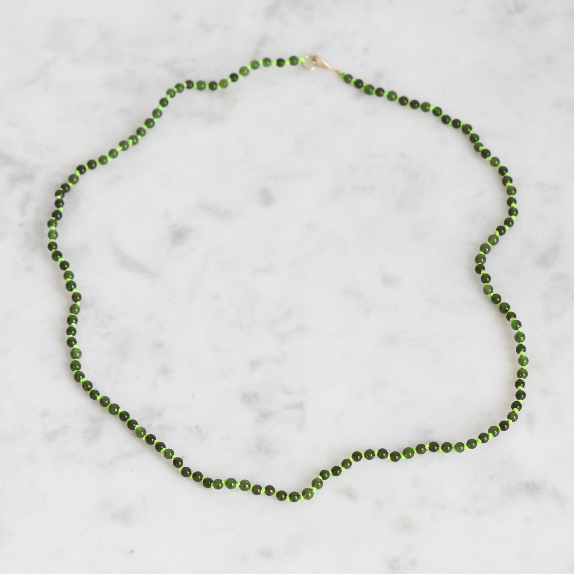 Green beaded necklace on a marble surface