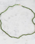 Green beaded necklace on a marble surface