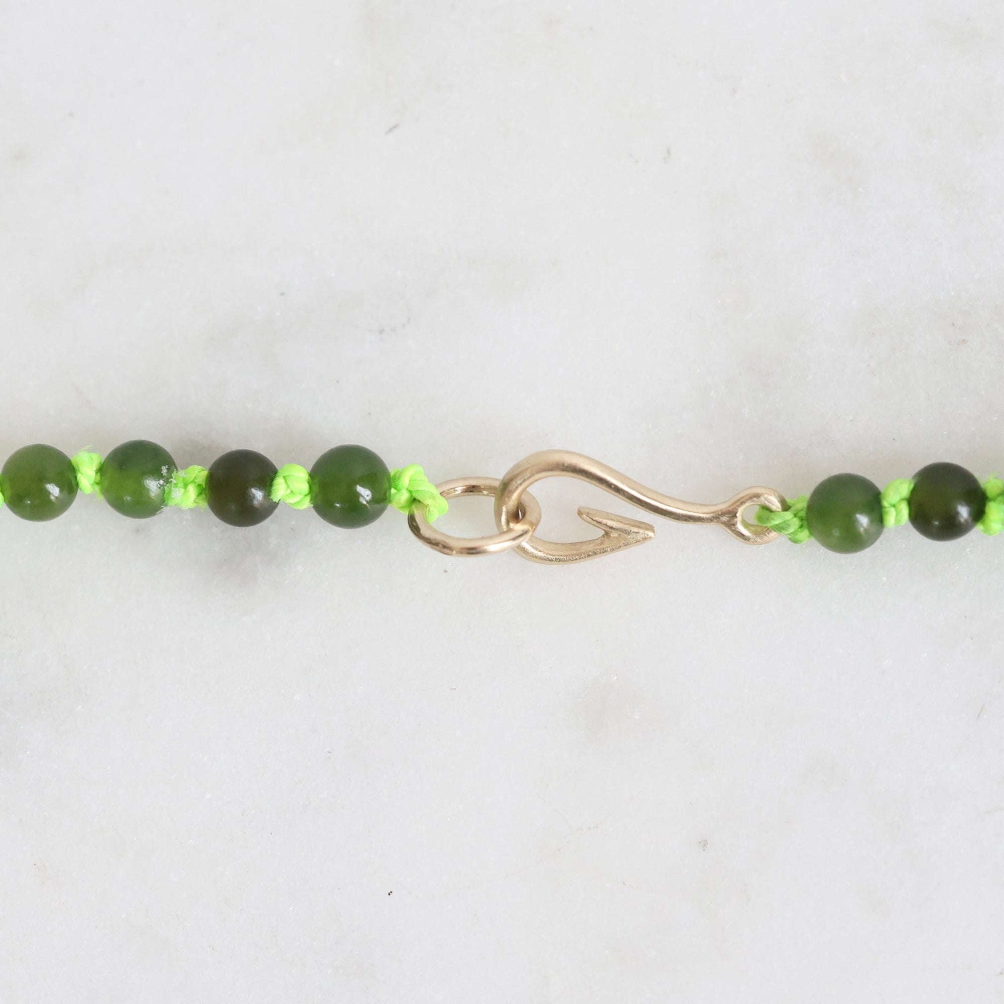 Green beaded necklace with a gold clasp on a white background