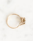 A gold ring with a small central stone, photographed from above on a light marble surface.