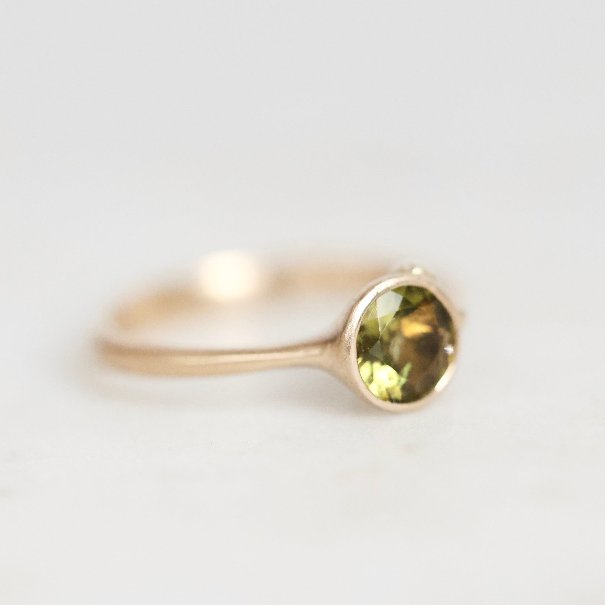 Gold ring with green gemstone on a white background 