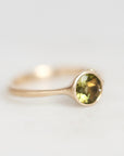 Gold ring with green gemstone on a white background 