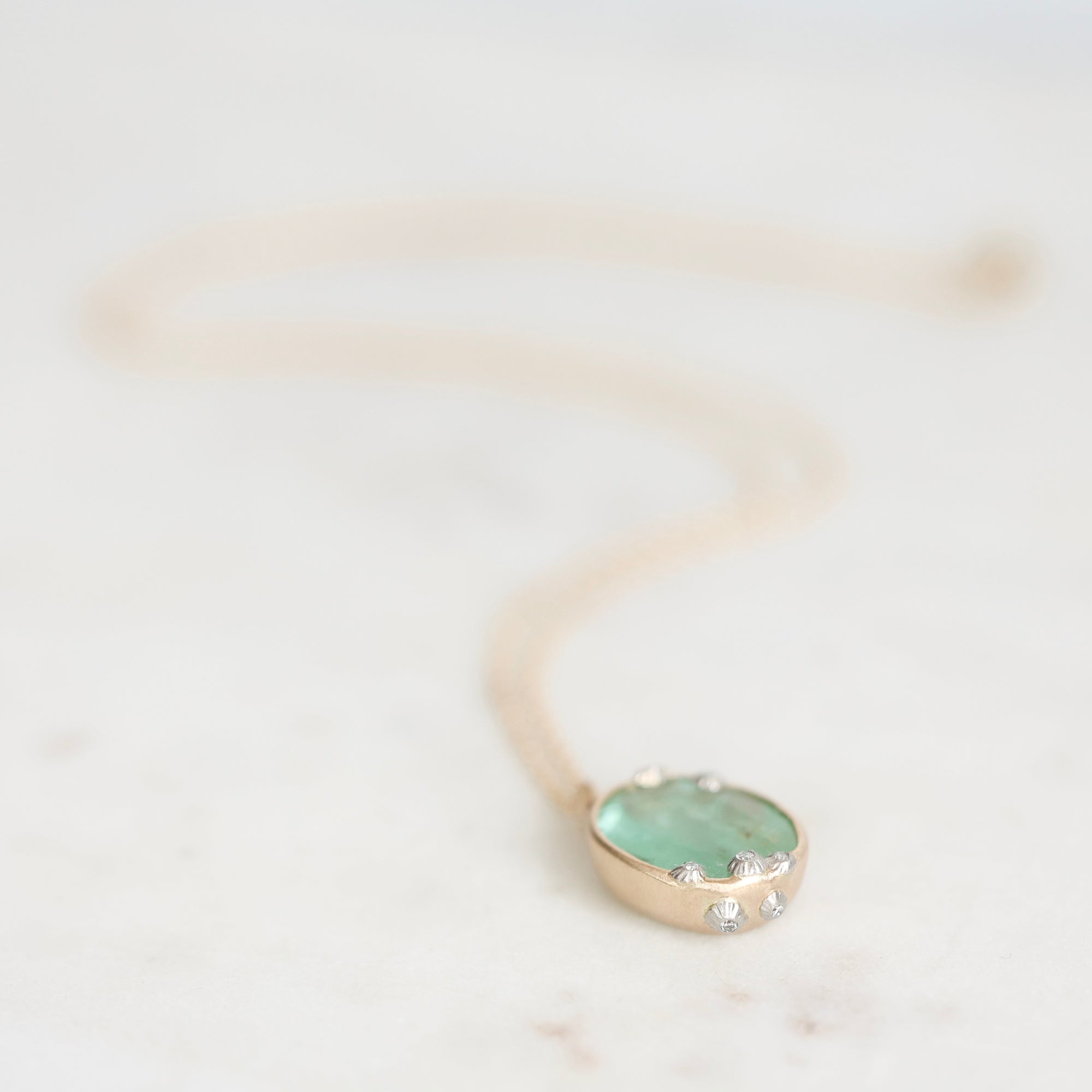 Emerald necklace laying on marble with barnacle details