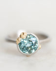 Platinum bezel set aquamarine ring with gold barnacle accents.