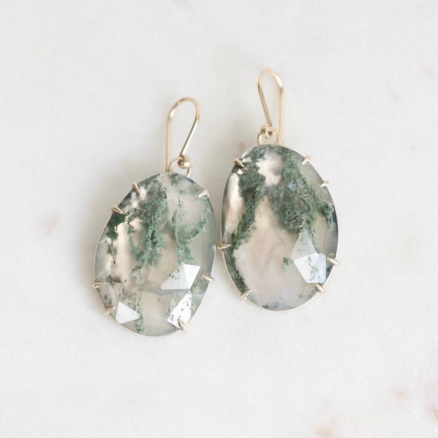 Moss agate earrings on marble background