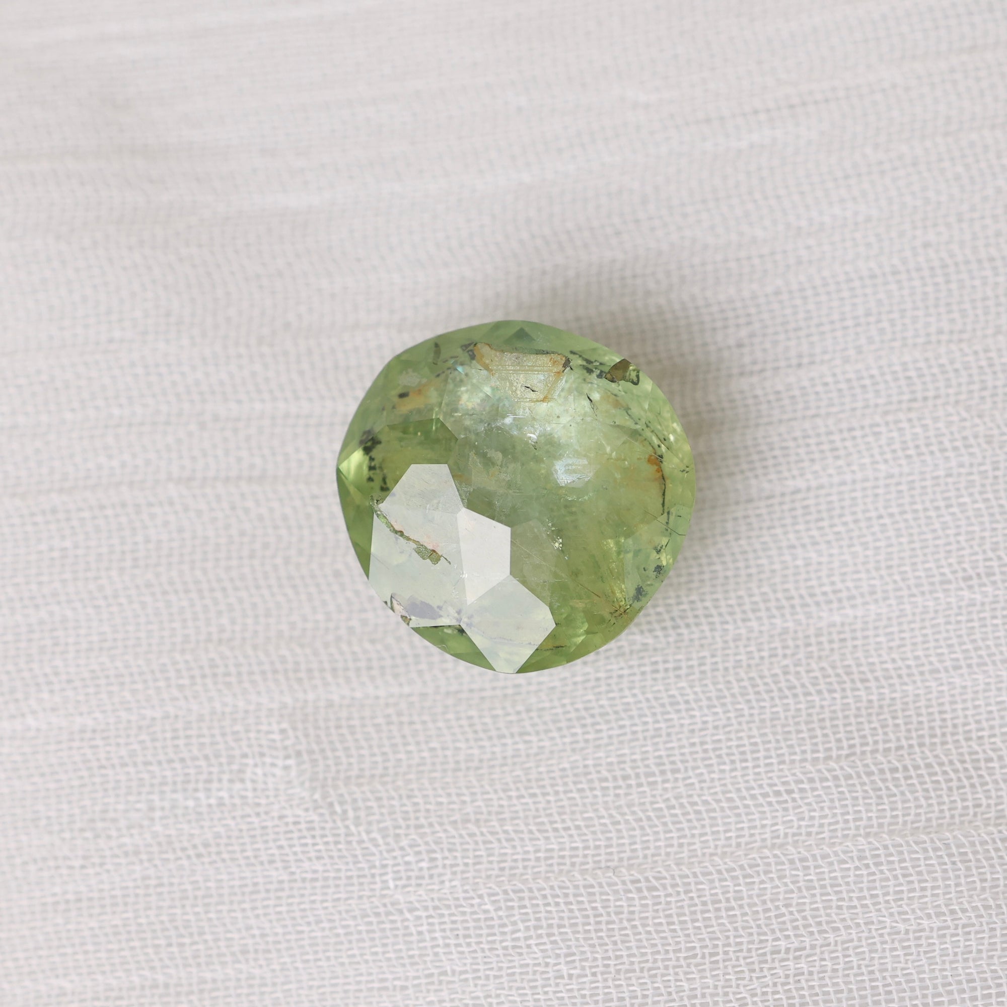 Green gemstone on textured white backgrounf