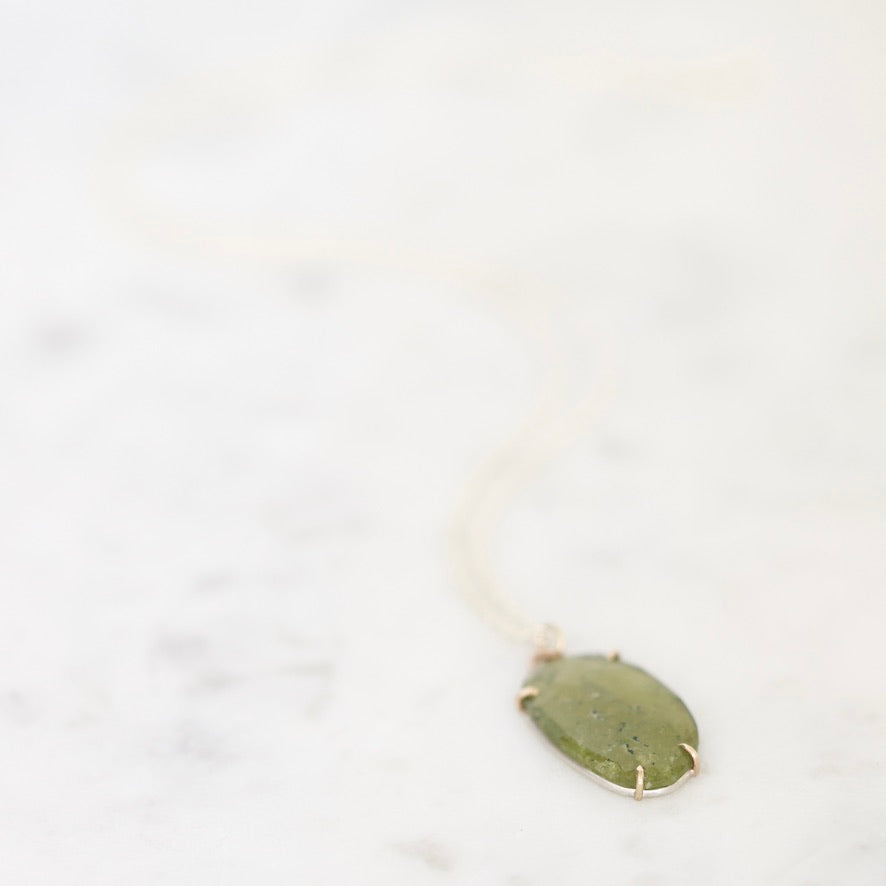 Green gemstone necklace on marble background