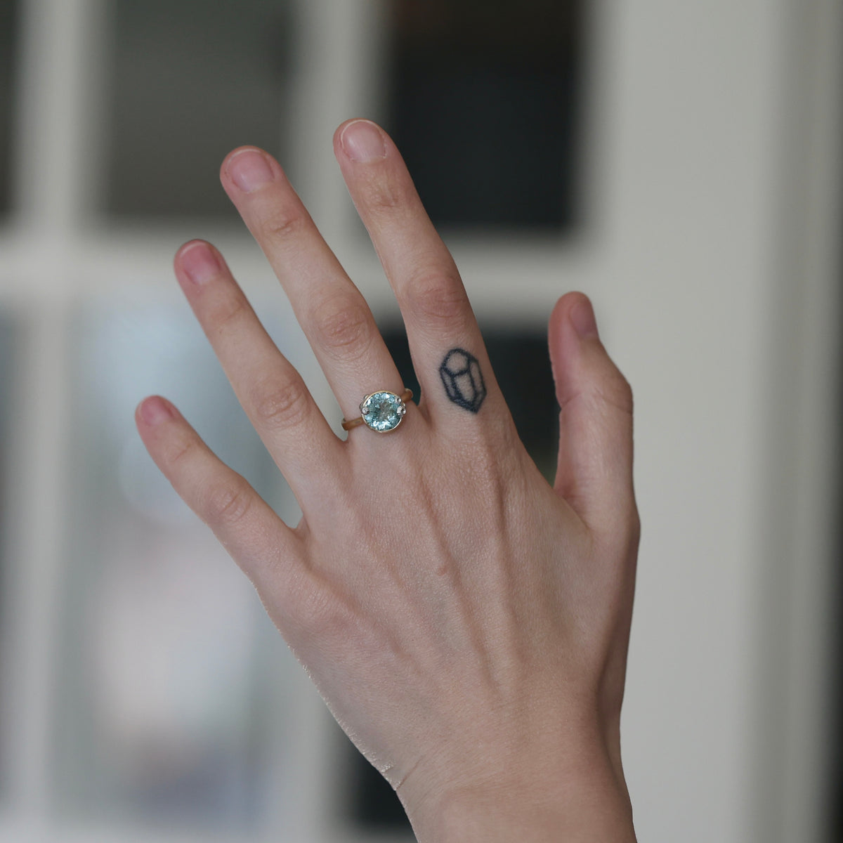 Hand wearing large aquamarine gemstone ring. 
