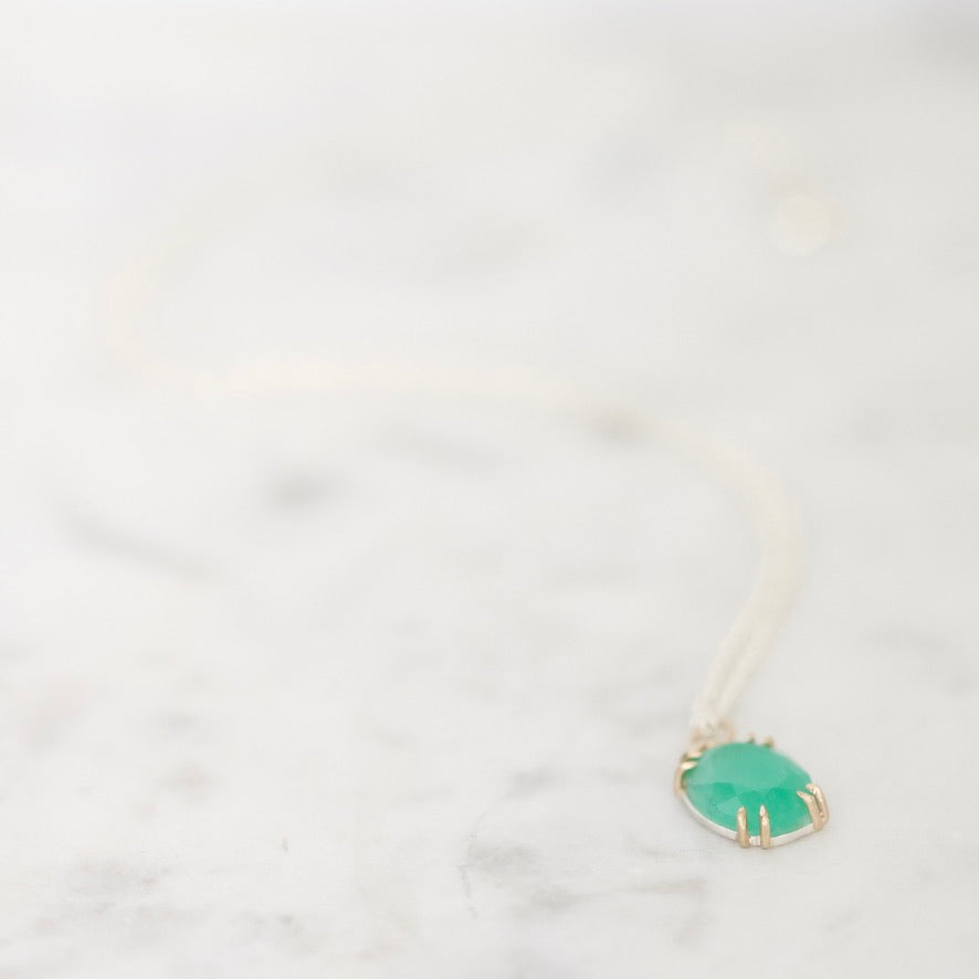 Green gemstone pendant on marble backround