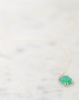 Green gemstone pendant on marble backround