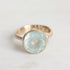 Gold ring with a large, faceted aquamarine stone on a light background