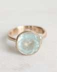 Gold ring with a large, faceted aquamarine stone on a light background