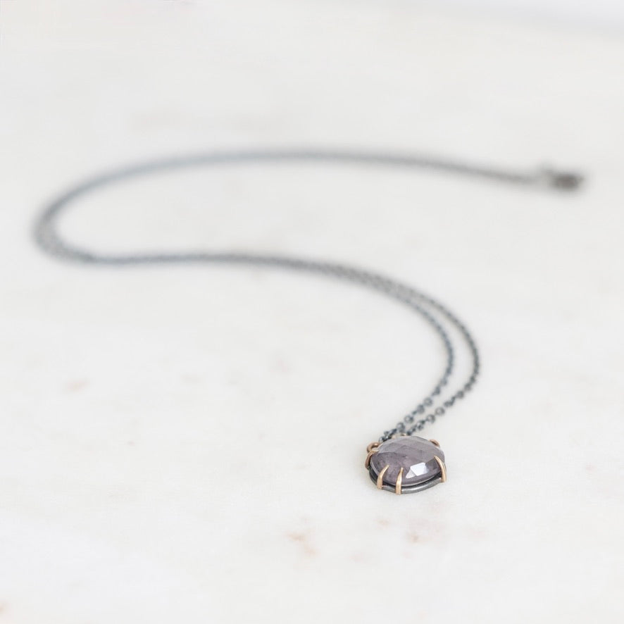 Purple spinel necklace with oxidized chain on marble surface