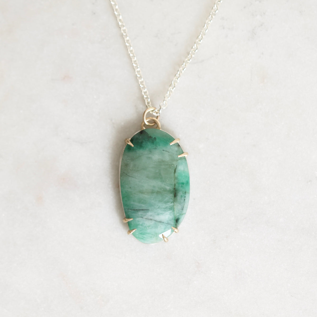 Green stone necklace with gold prongs close up