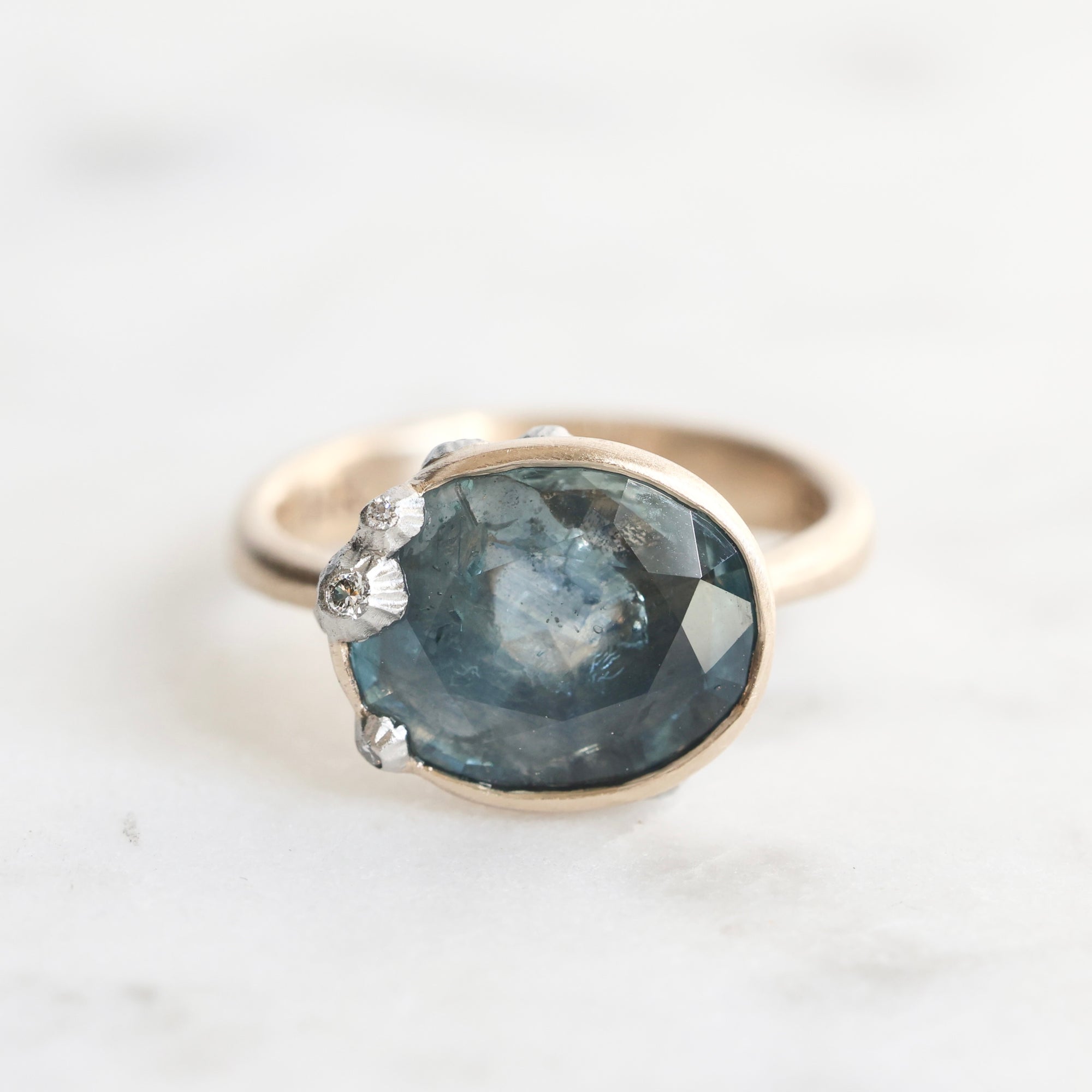 Ring with a blue gemstone and gold band on a white background