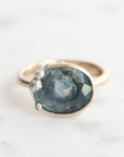 Ring with a blue gemstone and gold band on a white background