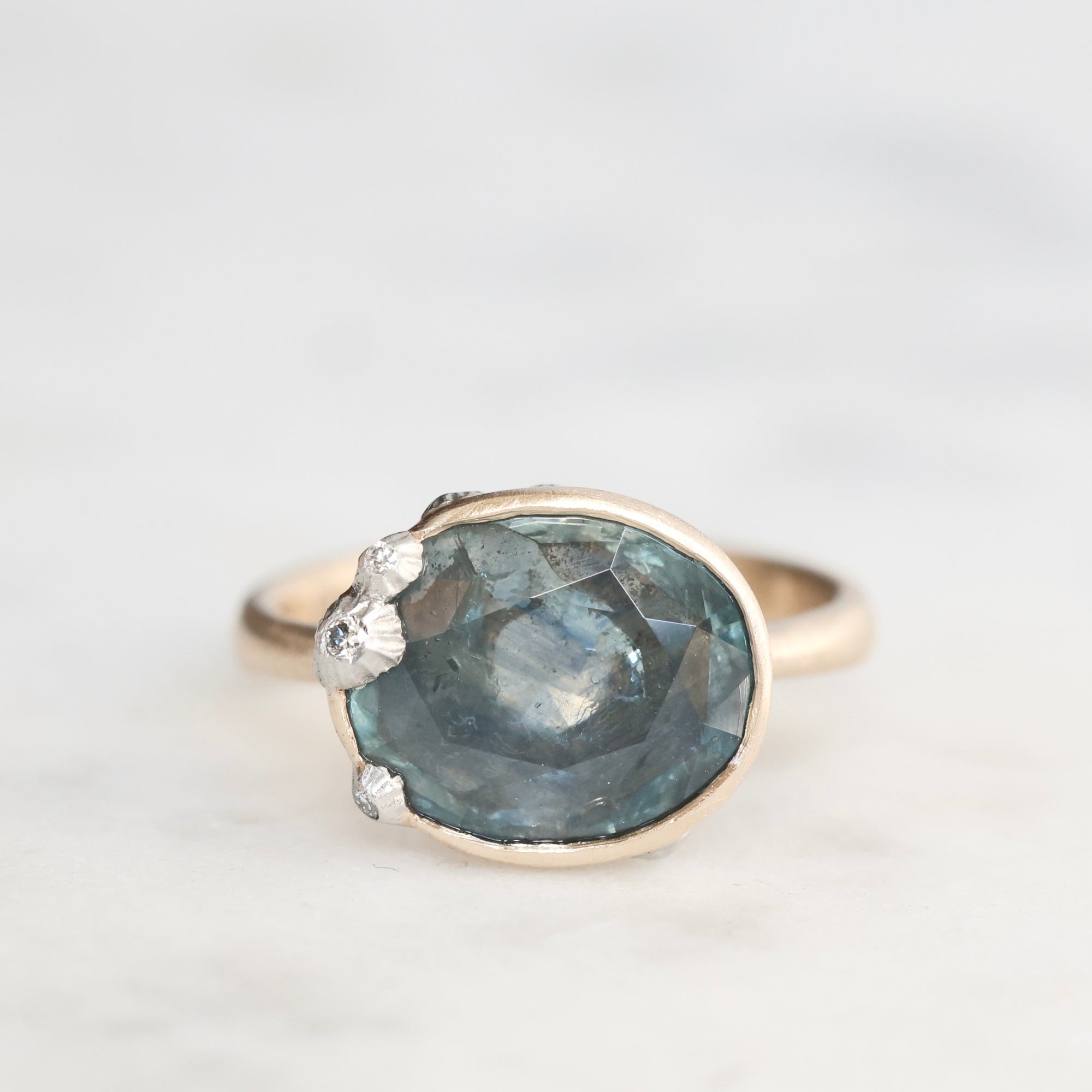 Ring with a large blue gemstone and smaller clear stones on a light gray background