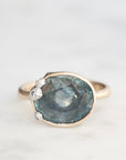 Ring with a large blue gemstone and smaller clear stones on a light gray background