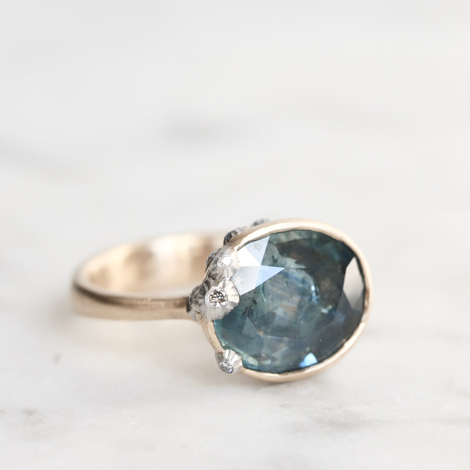 Ring with a large blue gemstone and smaller diamonds on a light background