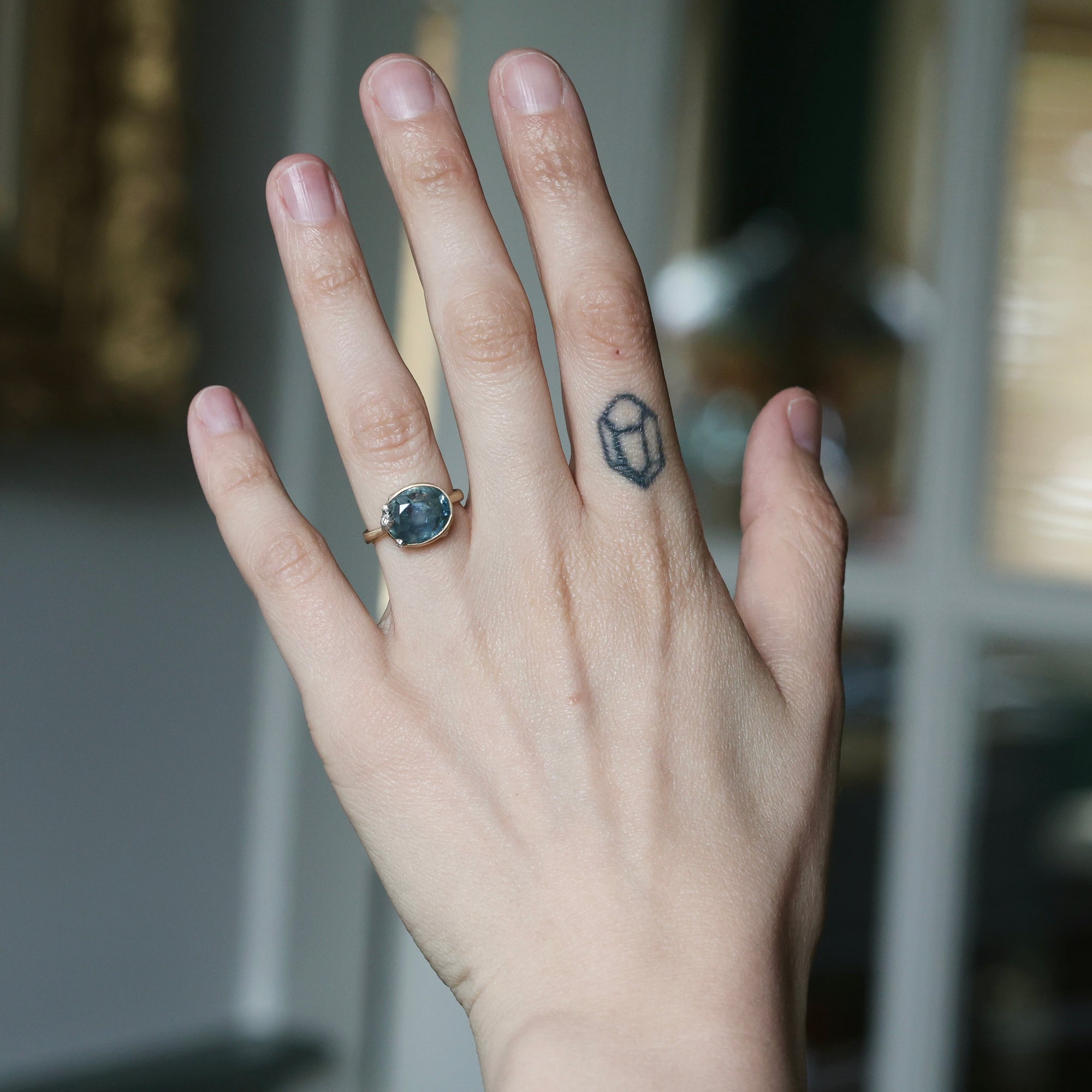 Hand with a ring and tattoo on a blurred background