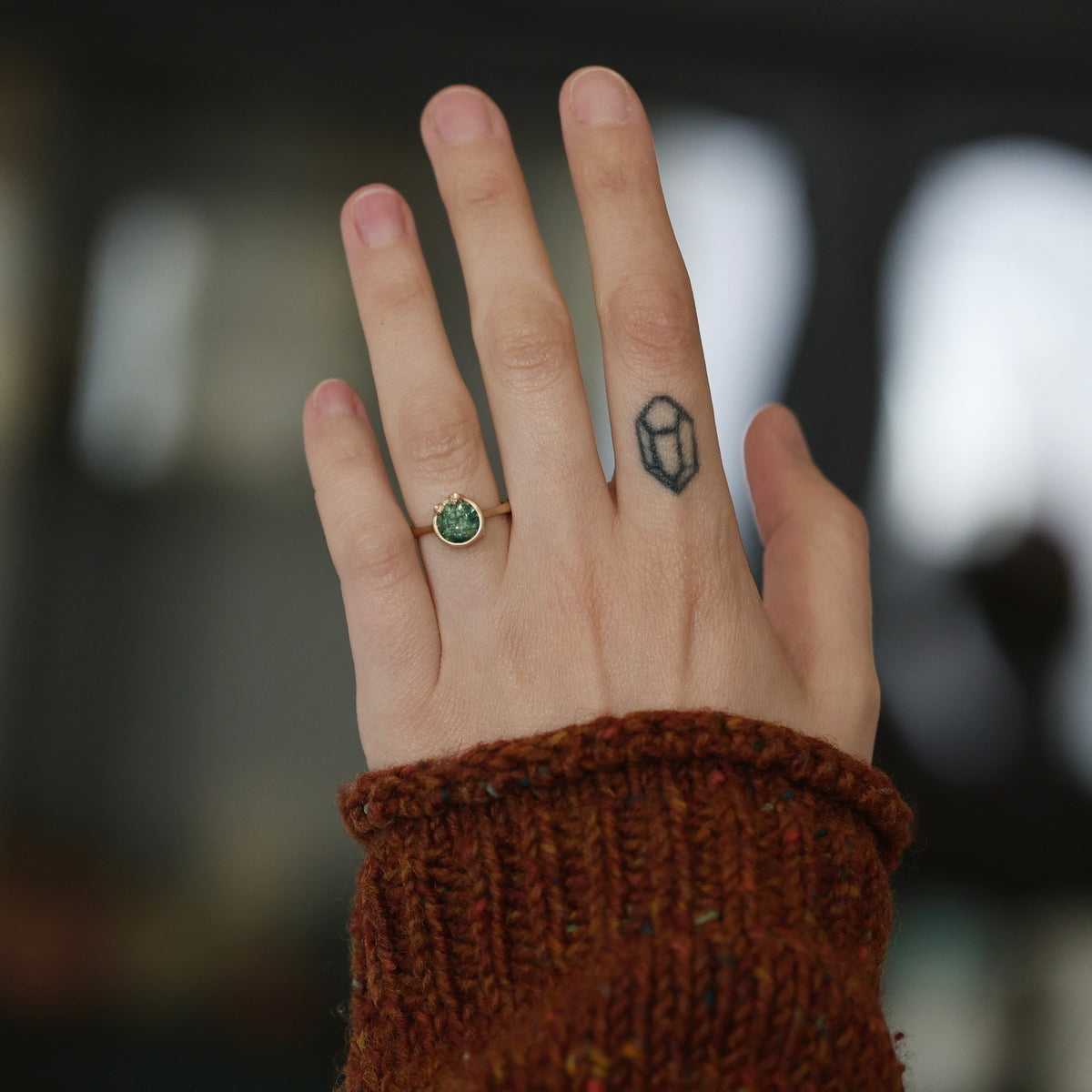 hand wearing green gemstone ring. 