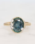 Ring with a blue gemstone and gold setting on a light gray background